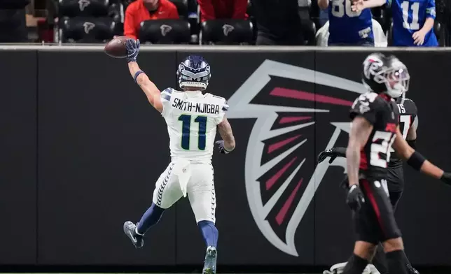 Seattle Seahawks wide receiver Jaxon Smith-Njigba holds up the ball after scoring a touchdown against the Atlanta Falcons during the second half of an NFL football game, Sunday, Dec. 7, 2025, in Atlanta. (AP Photo/Mike Stewart)
