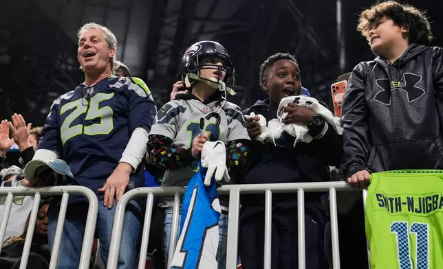 Fans react after getting gloves from Seattle Seahawks wide receiver Rashid Shaheed after an NFL football game against the Atlanta Falcons, Sunday, Dec. 7, 2025, in Atlanta. (AP Photo/Brynn Anderson)