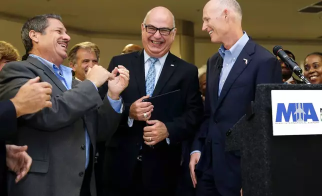 FILE - Florida Gov. Rick Scott, right, laughs with Emilio Gonzalez, director and chief executive officer of the Miami-Dade Aviation Department, center, and Jose "Pepe" Diaz, Miami-Dade County commissioner, left, after a news conference at Miami International Airport, Wednesday, Aug. 19, 2015, in Miami. (AP Photo/Lynne Sladky, File)