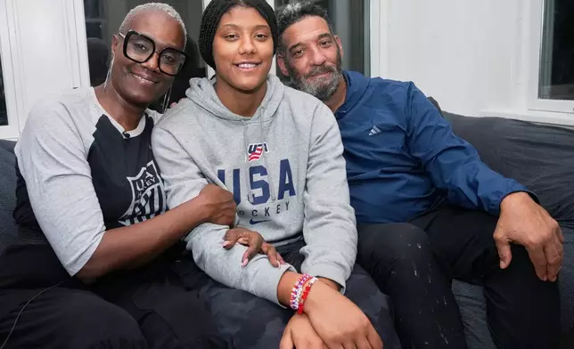 Laila Edwards, center, the first Black woman to suit up for Team USA women's Olympic hockey, poses for a photo with her parents, Charone Gray-Edwards, left, and Robert Edwards, right, in her childhood home in Cleveland Heights, Ohio, Wednesday, Nov. 5, 2025. (AP Photo/Sue Ogrocki)