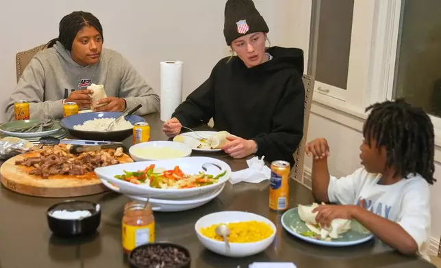 Laila Edwards, left, the first Black woman to suit up for Team USA women's Olympic hockey, teammate Caroline Harvey, center, and Laila's nephew Shiloh Stewart, right, talk during a family dinner at her childhood home in Cleveland Heights, Ohio, Wednesday, Nov. 5, 2025. (AP Photo/Sue Ogrocki)
