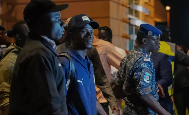 Senegal's Sadio Mane, center, is accompanied by securities as the team arrives following their victory in the Africa Cup of Nations soccer tournament, in Ndiass, Senegal, Tuesday, Jan. 20, 2026. (AP Photo/Misper Apawu)