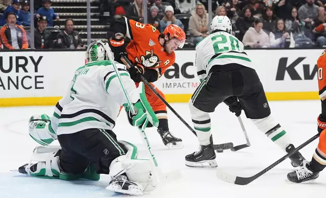 Anaheim Ducks center Mason McTavish, center, shoots as Dallas Stars goaltender Casey DeSmith, left, and defenseman Alexander Petrovic defend during the first period of an NHL hockey game Tuesday, Jan. 13, 2026, in Anaheim, Calif. (AP Photo/Gregory Bull)