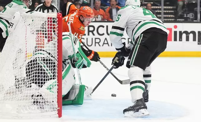 Anaheim Ducks right wing Beckett Sennecke, behind, scores a goal as Dallas Stars goaltender Casey DeSmith, left, and defenseman Ilya Lyubushkin defend during the third period of an NHL hockey game Tuesday, Jan. 13, 2026, in Anaheim, Calif. (AP Photo/Gregory Bull)