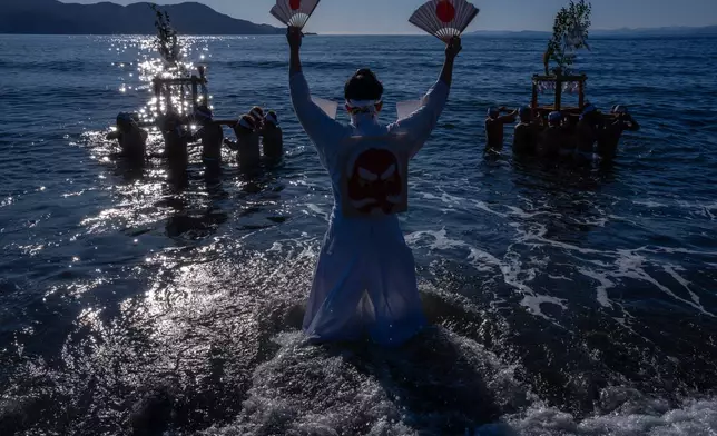 Participants carry a portable shrine 'mikoshi', during the Winter Sea Misogi Festival, a Shinto purification ritual marking the New Year, in Numazu, Japan, Monday, Jan. 12, 2026. (AP Photo/Louise Delmotte)