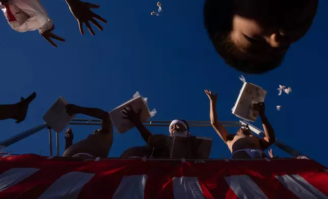 Participants throw rice cakes to the public after the Winter Sea Misogi Festival, a Shinto purification ritual marking the New Year, in Numazu, Japan, Monday, Jan. 12, 2026. (AP Photo/Louise Delmotte)