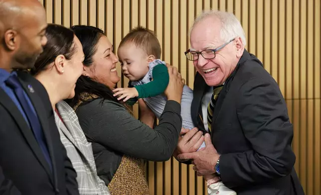 Gov. Tim Walz smiles at a child before speaking during a press conference on Tuesday, Jan. 6, 2026 at the Coliseum Building in Minneapolis. (Kerem Yücel/Minnesota Public Radio via AP)
