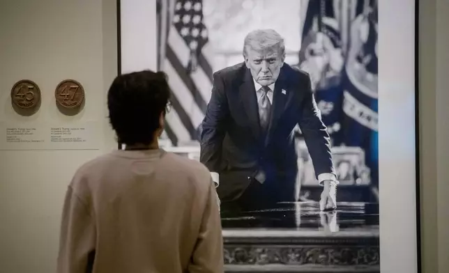 A visitor stops to look at a photograph of President Donald Trump and a short plaque next to it are on display at the Smithsonian's National Portrait Gallery's "American Presidents" exhibit on Sunday, Jan. 11, 2026 in Washington. (AP Photo/Rod Lamkey, Jr.)