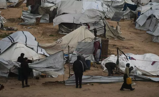 Palestinians repair their tents after they were damaged by a storm at a displacement camp in Gaza City, Tuesday, Jan. 13, 2026. (AP Photo/Jehad Alshrafi)