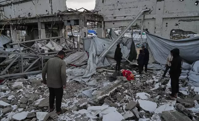 People inspect the site where at least four Palestinians died following the collapse of walls onto tents sheltering displaced people in Gaza City amid rainfall and strong winds, Tuesday, Jan. 13, 2026. (AP Photo/Jehad Alshrafi)