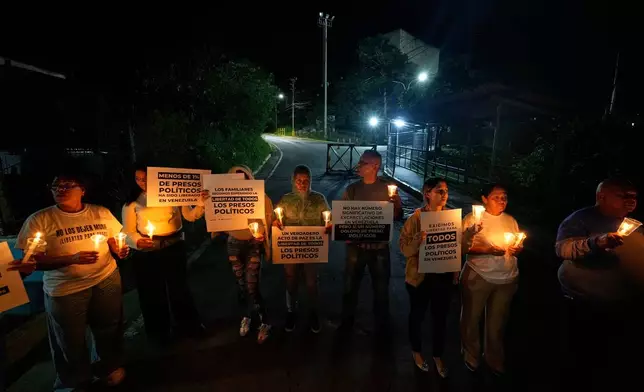 Relatives and friends of political prisoners hold banners and candles calling for their loved ones to be set free outside the Rodeo I prison in Guatire, Venezuela, Friday, Jan. 9, 2026 after the government announced prisoners would be released. (AP Photo/Matias Delacroix)