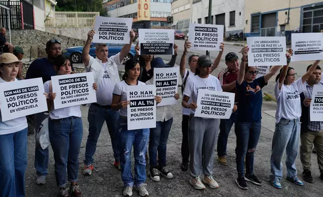 Relatives and friends of political prisoners hold banners calling for their loved ones to be set free outside El Helicoide, the headquarters of Venezuela's intelligence service and detention center, in Caracas, Venezuela, Friday, Jan. 9, 2026 after the government announced prisoners would be released.(AP Photo/Ariana Cubillos)