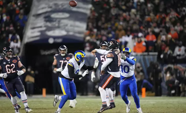 Chicago Bears quarterback Caleb Williams (18) throws a touchdown pass to tight end Cole Kmet, not visible, as Los Angeles Rams linebacker Josaiah Stewart (10) and linebacker Jared Verse (8) apply pressure during the second half of an NFL football divisional playoff game Sunday, Jan. 18, 2026, in Chicago. (AP Photo/Jeff Roberson)