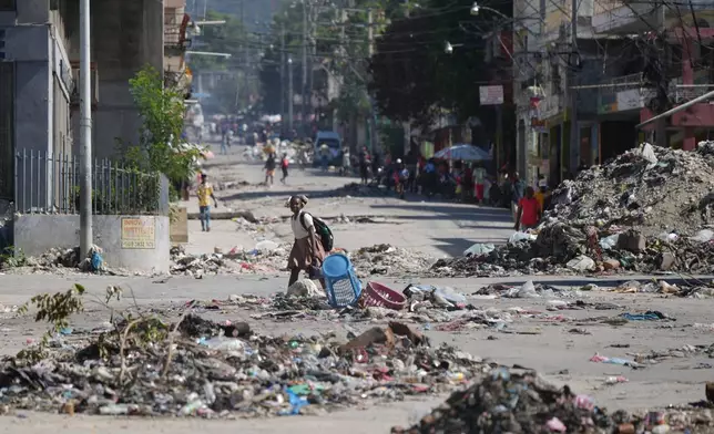 A youth crosses a street littered with garbage in downtown in Port-au-Prince, Haiti, Tuesday, Jan. 20, 2026. (AP Photo/Odelyn Joseph)