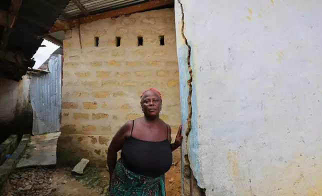 Marie Pearl stands by her house, which has developed cracks that she blames on blasting at a nearby mine site in Gold Camp, Liberia, July 8, 2025. (AP Photo/Misper Apawu)