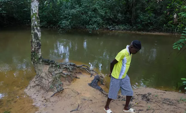 Mustapha Pabai, the town chief, walks beside a polluted river, in Jikando, Liberia, July 8, 2025. (AP Photo/Misper Apawu)