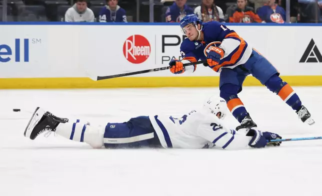 New York Islanders center Mathew Barzal, top, shoots the puck past Toronto Maple Leafs defenseman Jake McCabe during the second period of an NHL hockey game, Saturday, Jan. 3, 2026, in Elmont, N.Y. (AP Photo/Heather Khalifa)