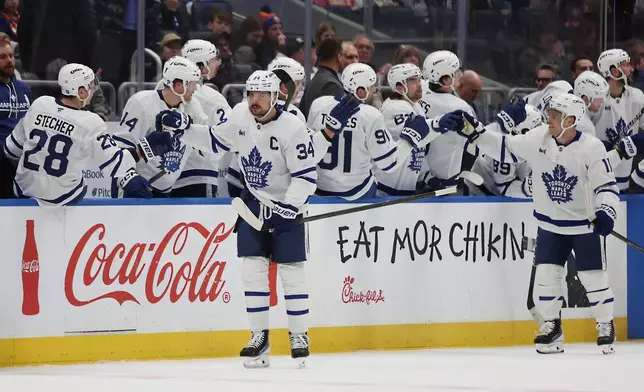 Toronto Maple Leafs center Auston Matthews (34), left, high-fives teammates after scoring during the second period of an NHL hockey game against the New York Islanders, Saturday, Jan. 3, 2026, in Elmont, N.Y. (AP Photo/Heather Khalifa)