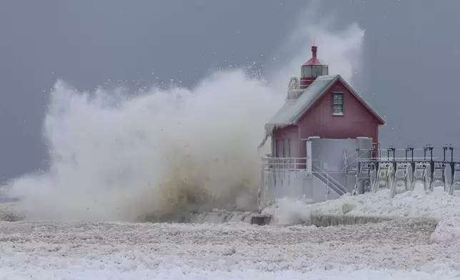 A large wave from Lake Michigan sends ice balls into the air as it crashes into the South Pierhead Outer Light at Grand Haven State Park in Grand Haven, Mich., Monday, Jan. 19, 2026. (Joel Bissell/Kalamazoo Gazette via AP)