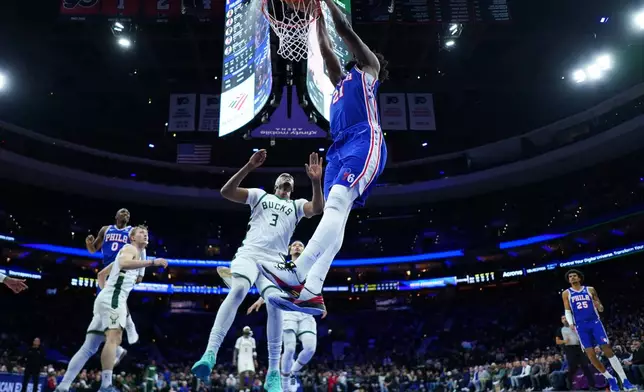 Philadelphia 76ers' Joel Embiid, right, dunks past Milwaukee Bucks' Myles Turner during the first half of an NBA basketball game Tuesday, Jan. 27, 2026, in Philadelphia. (AP Photo/Matt Slocum)