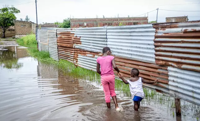 Children wade through floodwaters in a neighborhood in Maputo, Mozambique, on Friday, Jan. 16, 2026. (AP Photo/Carlos Uqueio)