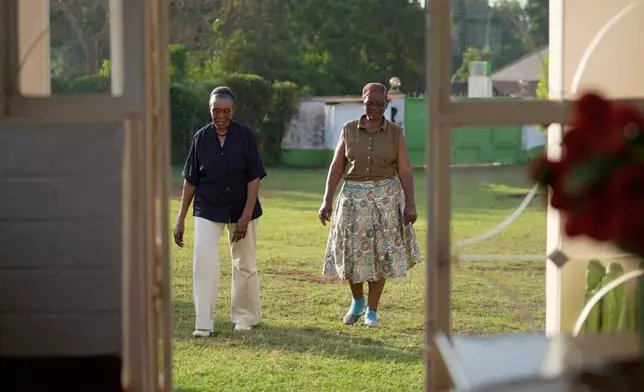 Widows Rebecca Anyango, 70 years old, right, and Marie Owino, 87 years old, a former teacher, left, walk outside Marie's compound home in Siaya, Kenya, Thursday, Nov. 27, 2025. (AP Photo/Brian Inganga)