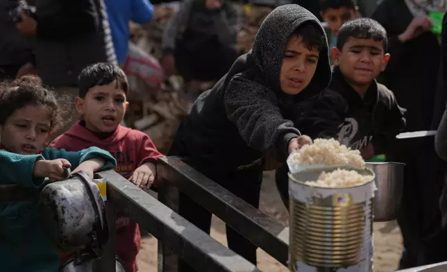 Palestinian children receive donated food at a community kitchen in Nuseirat, in central Gaza Strip, Saturday, Jan. 24, 2026. (AP Photo/Abdel Kareem Hana)