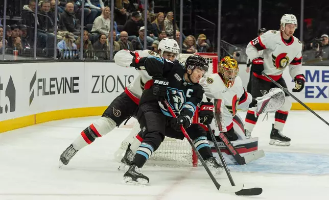 Utah Mammoth center Clayton Keller (9) moves the puck against Ottawa Senators center Shane Pinto (12) and goaltender Mads Sogaard (40) during the first period of an NHL hockey game Wednesday, Jan. 7, 2026, in Salt Lake City. (AP Photo/Melissa Majchrzak)