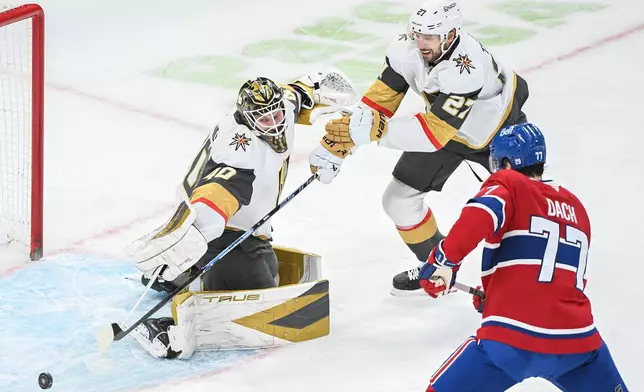 Montreal Canadiens' Kirby Dach (77) moves in on Vegas Golden Knights goaltender Akira Schmid (40) as Knights' Shea Theodore (27) defends during the first period of an NHL hockey game in Montreal, Tuesday, Jan. 27, 2026. (Graham Hughes/The Canadian Press via AP)