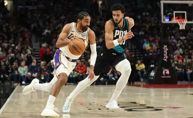 Los Angeles Lakers guard Gabe Vincent, left, drives to the basket as Portland Trail Blazers forward Toumani Camara, right, defends during the first half of an NBA basketball game Saturday, Jan. 17, 2026, in Portland, Ore. (AP Photo/Amanda Loman)