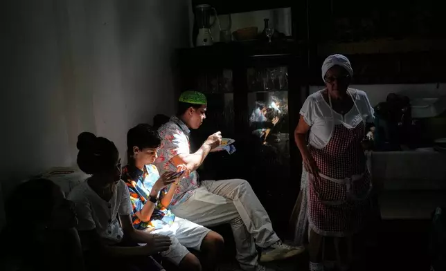 Santeria priests, also known as Babalawo, eat after a cleansing ritual with roosters during a ceremony calling for peace and health in Havana, Sunday, Jan. 25, 2026. (AP Photo/Ramon Espinosa)