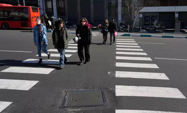People cross an intersection in downtown Tehran, Iran, Friday, Jan. 16, 2026. (AP Photo/Vahid Salemi)