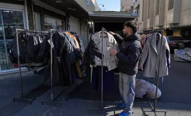 A street vendor adjusts clothes for sale in downtown Tehran, Iran, Friday, Jan. 16, 2026. (AP Photo/Vahid Salemi)