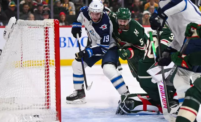 Winnipeg Jets center Jonathan Toews (19) scores a goal as he's checked by Minnesota Wild defenseman Jake Middleton (5) during the first period of an NHL hockey game Thursday, Jan. 15, 2025, in St. Paul, Minn. (AP Photo/Craig Lassig)