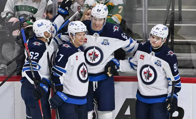 Winnipeg Jets defenseman Logan Stanley, second from right, celebrates with right wing Nino Niederreiter (62), center Vladislav Namestnikov (7) and center Cole Perfetti (91) after scoring against the Minnesota Wild during the second period of an NHL hockey game, Thursday, Jan. 15, 2025, in St. Paul, Minn. (AP Photo/Craig Lassig)