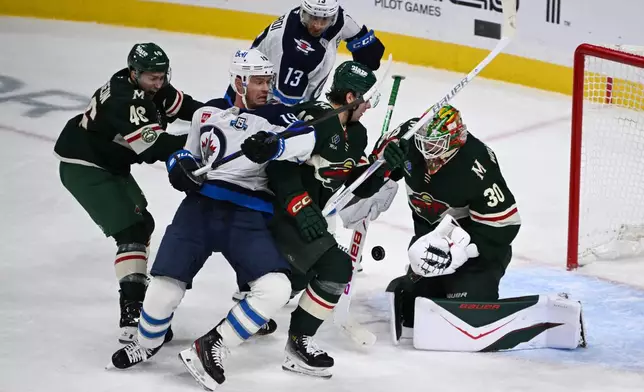 Minnesota Wild goaltender Jesper Wallstedt (30) stops a shot as defenseman Jared Spurgeon, left and defenseman Daemon Hunt, second from right, tries to clear Winnipeg Jets center Jonathan Toews (19) and center Gabriel Vilardi (13) from the goal during the second period of an NHL hockey game Thursday, Jan. 15, 2025, in St. Paul, Minn. (AP Photo/Craig Lassig)