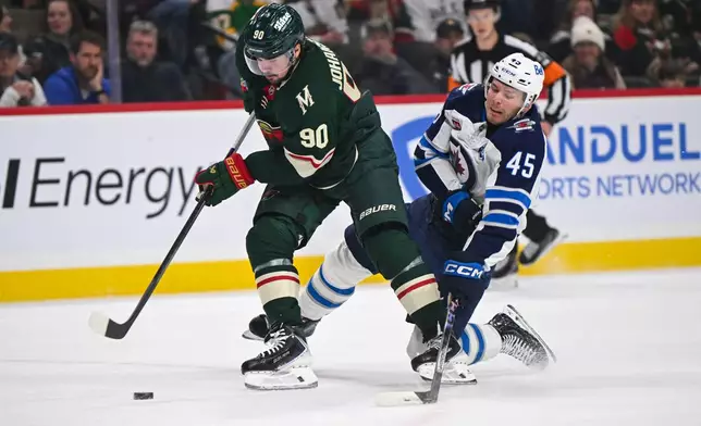 Winnipeg Jets left wing Cole Koepke (45) tries to slap the puck away from Minnesota Wild left wing Marcus Johansson (90) during the first period of an NHL hockey game, Thursday, Jan. 15, 2025, in St. Paul, Minn. (AP Photo/Craig Lassig)