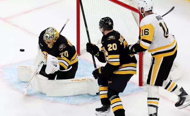 Boston Bruins goaltender Joonas Korpisalo (70) makes a glove-save as teammate Henri Jokiharju (20) and Pittsburgh Penguins right wing Justin Brazeau (16) watch during the second period of an NHL hockey game, Sunday, Jan. 11, 2026, in Boston. (AP Photo/Mark Stockwell)