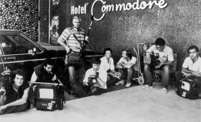 FILE - Television crews, some wearing flak jackets, crouch down in front of the Commodore Hotel, in West Beirut, on Aug. 31,1983, as the Lebanese Army battles with Shiite and Druse militiamen. (AP Photo/Bill Foley, File)