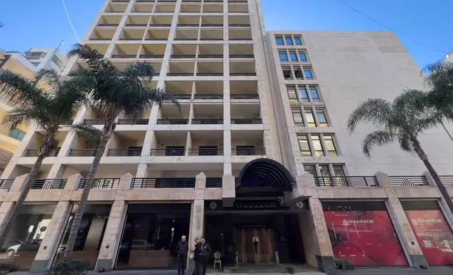 People stand outside the closed Commodore hotel, in Beirut, Lebanon, Sunday, Jan. 11, 2026. (AP Photo/Hussein Malla)