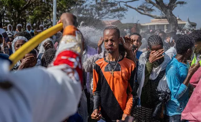 Holy water is sprayed on Ethiopian Orthodox worshippers, during the celebration of the Ethiopian Epiphany on lake Dembel, in Batu, Ethiopia, Monday, Jan. 19, 2026. (AP Photo/Amanuel Sileshi)