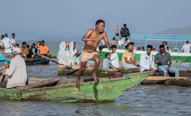 An Ethiopian orthodox believer jumps from a boat as faithful celebrate Timket, the Ethiopian Epiphany, on lake Dembel, in Batu, Ethiopia, Sunday, Jan. 18, 2026. (AP Photo/Amanuel Sileshi)
