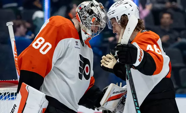 Philadelphia Flyers goaltender Dan Vladar, left, and Noah Cates (27) celebrate after defeating the Vancouver Canucks after the third period of an NHL game in Vancouver, on Tuesday, Dec. 30, 2025. (Ethan Cairns/The Canadian Press via AP)