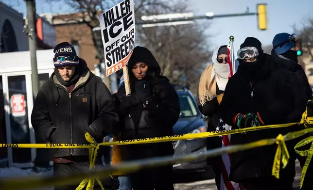 People gather at the site where a federal officer shot and killed 37-year-old Alex Pretti in Minneapolis on Saturday, Jan. 24, 2026. (Ben Hovland/Minnesota Public Radio via AP)