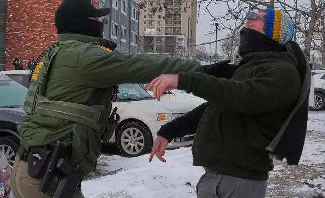 A person is pushed back by a federal agent working on the scene in Minneapolis, Sunday, Jan. 25, 2026. (AP Photo/Adam Gray)