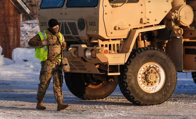A Minnesota National Guard member walks around with their weapon in front of the Bishop Henry Whipple Federal Building, Sunday, Jan. 25, 2026, in Minneapolis. (AP Photo/Adam Gray)