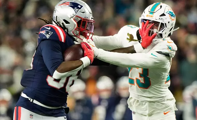 New England Patriots running back Rhamondre Stevenson, left, stiff arms Miami Dolphins cornerback while running for a touchdown during the second half of an NFL football game in Foxborough, Mass., Sunday, Jan. 4, 2026. (AP Photo/Robert F. Bukaty)