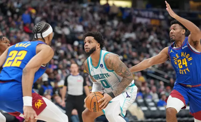 Charlotte Hornets forward Miles Bridges, center, drives to the net between Denver Nuggets forward Zeke Nnaji, left, and guard Jalen Pickett in the second half of an NBA basketball game Sunday, Jan. 18, 2026, in Denver. (AP Photo/David Zalubowski)