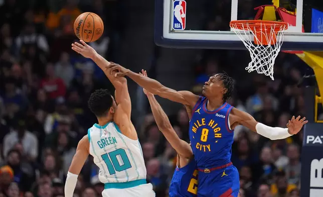 Denver Nuggets guard Peyton Watson, right, blocks a shot by Charlotte Hornets guard Josh Green, left, in the first half of an NBA basketball game Sunday, Jan. 18, 2026, in Denver. (AP Photo/David Zalubowski)