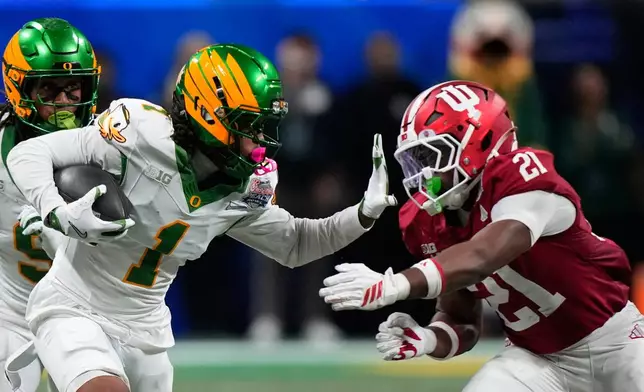 Oregon wide receiver Dakorien Moore (1) carries against Indiana linebacker Rolijah Hardy (21) during the second half of the Peach Bowl NCAA college football playoff semifinal, Friday, Jan. 9, 2026, in Atlanta. (AP Photo/Brynn Anderson)